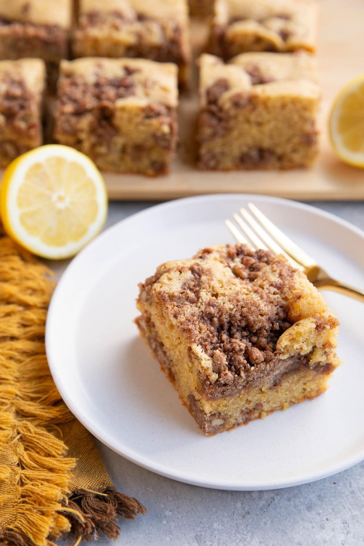 Slice of lemon coffee cake on a plate with slices of coffee cake in the background.