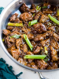 Stainless steel skillet full of healthy Mongolian beef with a blue napkin to the side. Ready to serve.