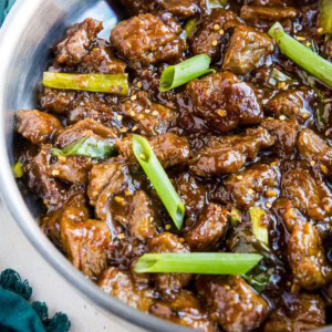 Stainless steel skillet full of healthy Mongolian beef with a blue napkin to the side. Ready to serve.