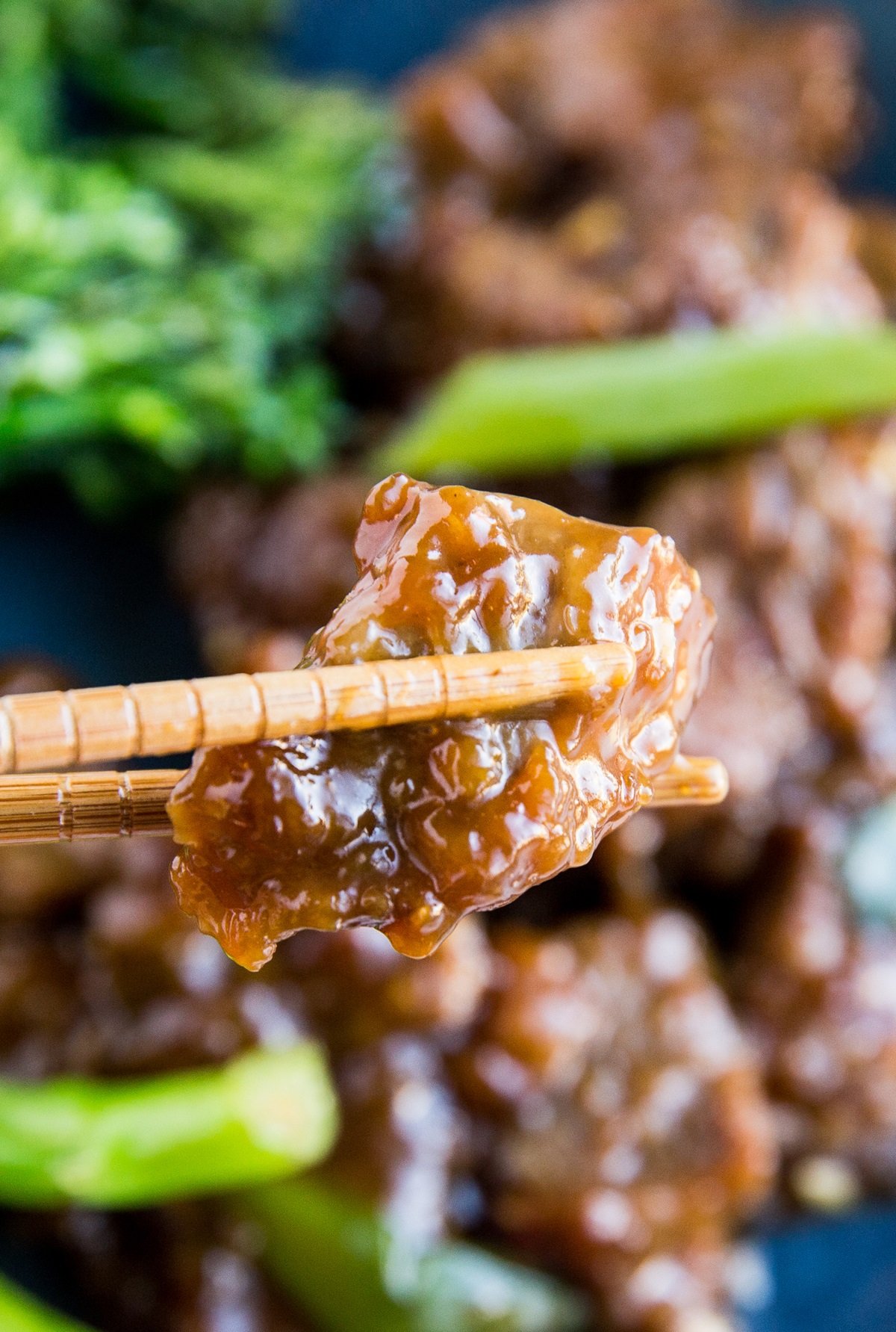 Chopstick picking up a piece of Mongolian beef so you can see the crispy, saucy deliciousness up close.