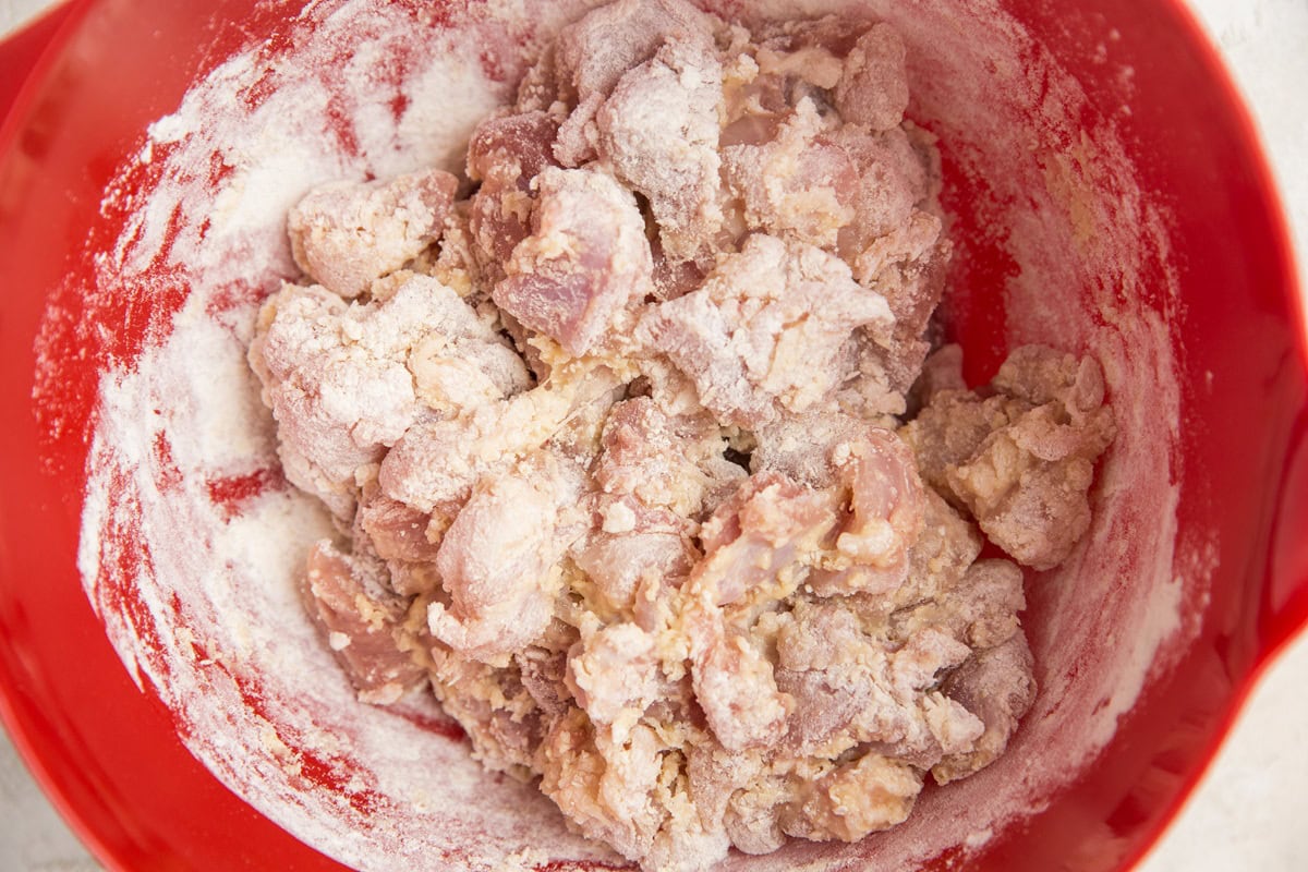 Mixing bowl with chicken coated in flour.