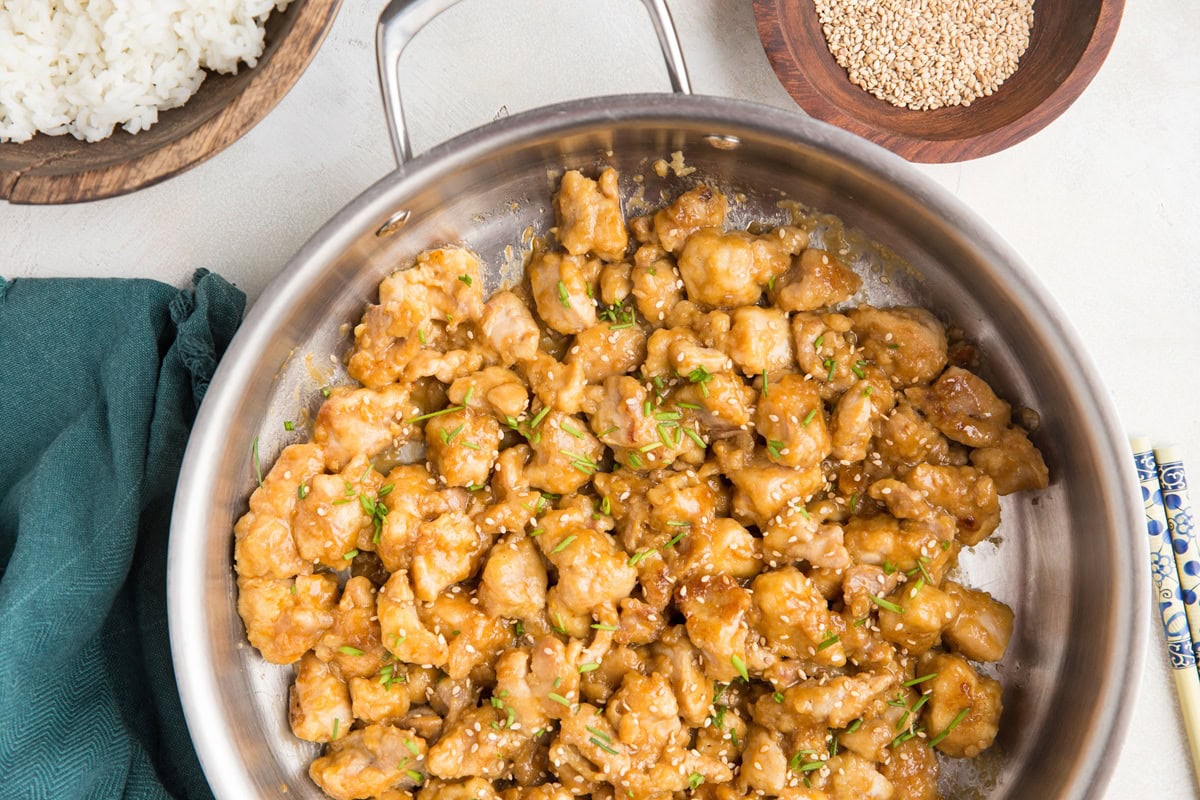 Stainless steel skillet with orange chicken inside.