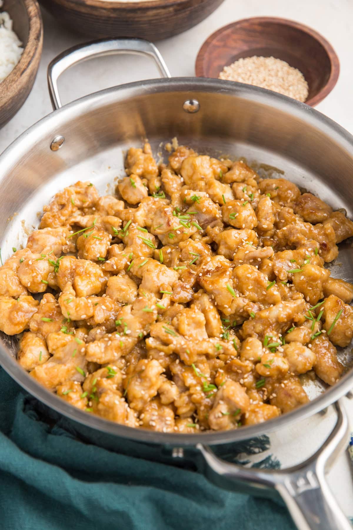 Stainless steel skillet full of orange chicken pieces.