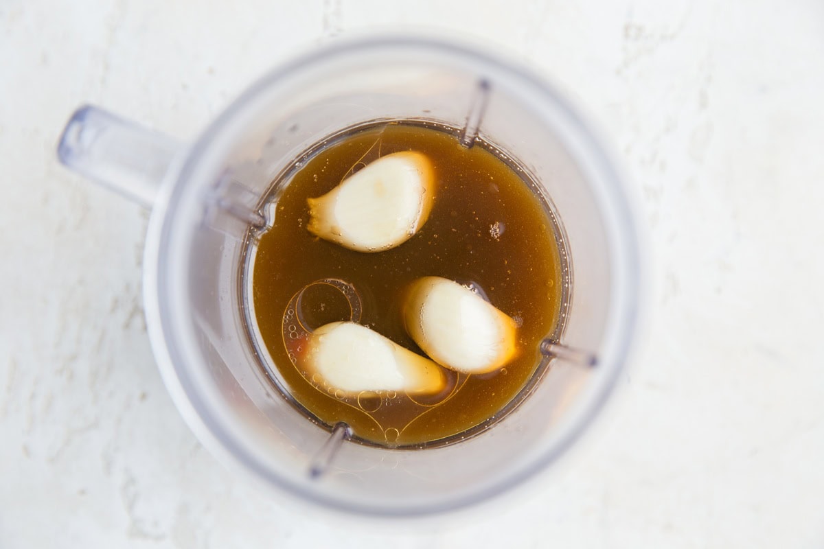 Small blender with orange sauce ingredients inside, ready to be blended
