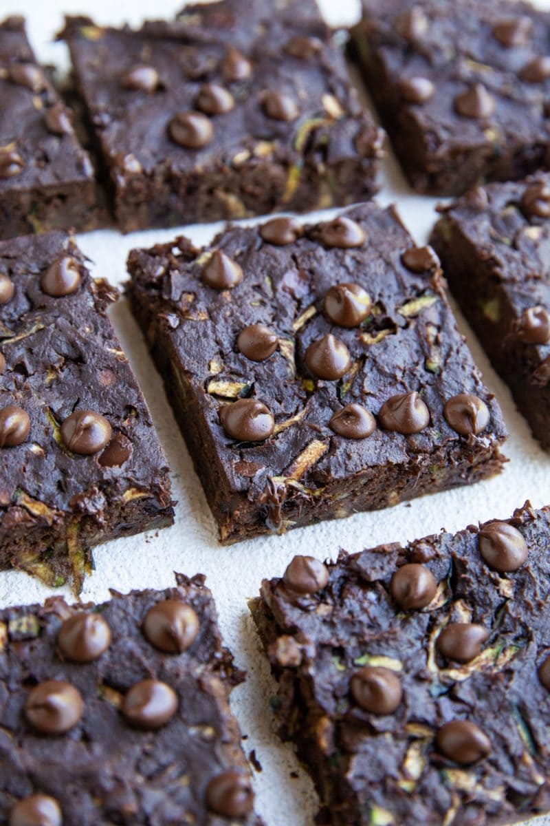 Zucchini brownies cut up into squares on a white background.