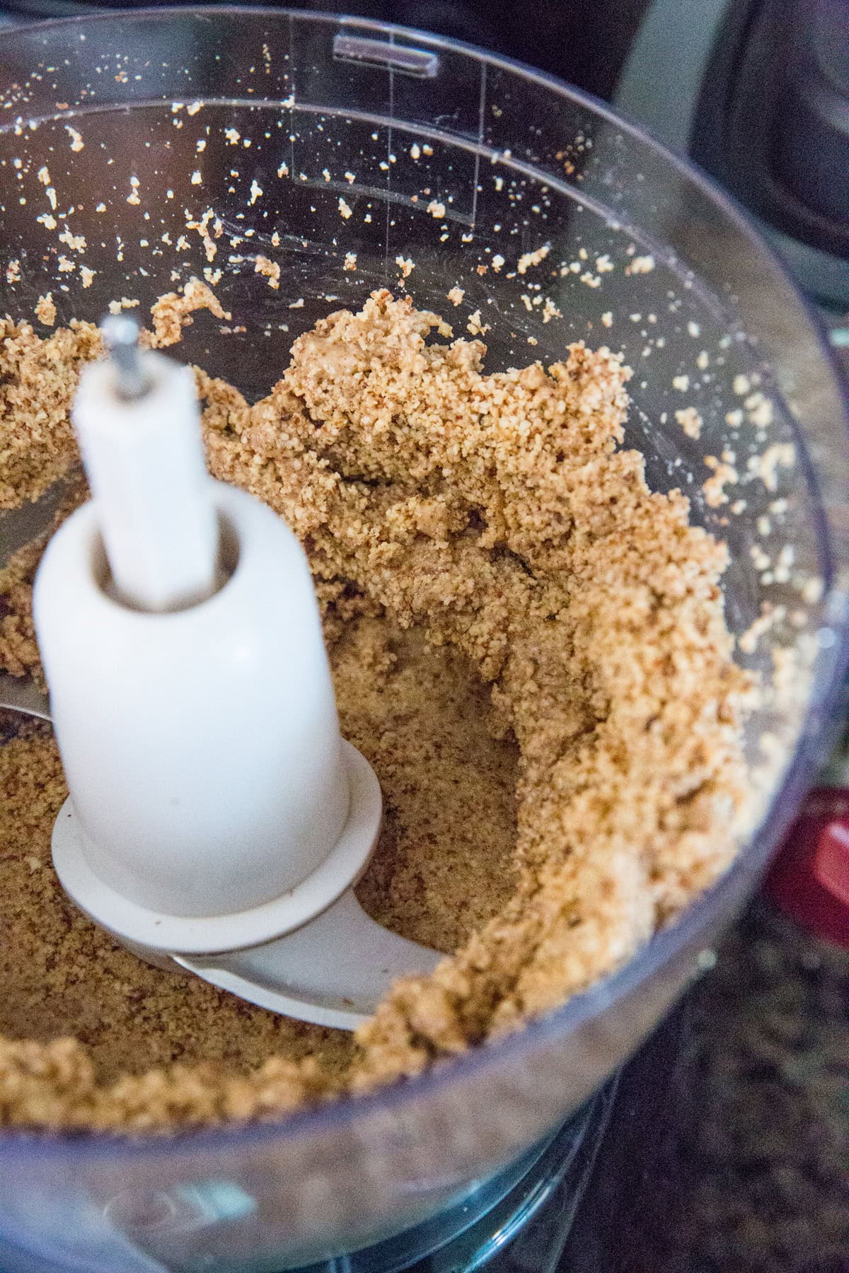 Ground up almonds in a food processor, in the middle of making homemade nut butter.
