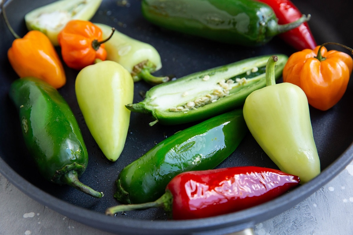 Skillet with peppers and chilies sautéing to soften up.