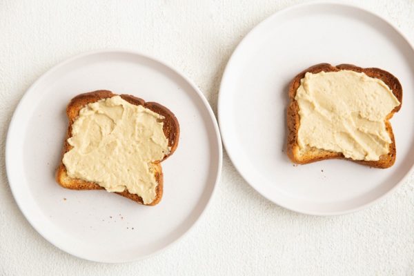 Two slices of toast with hummus smeared on top.