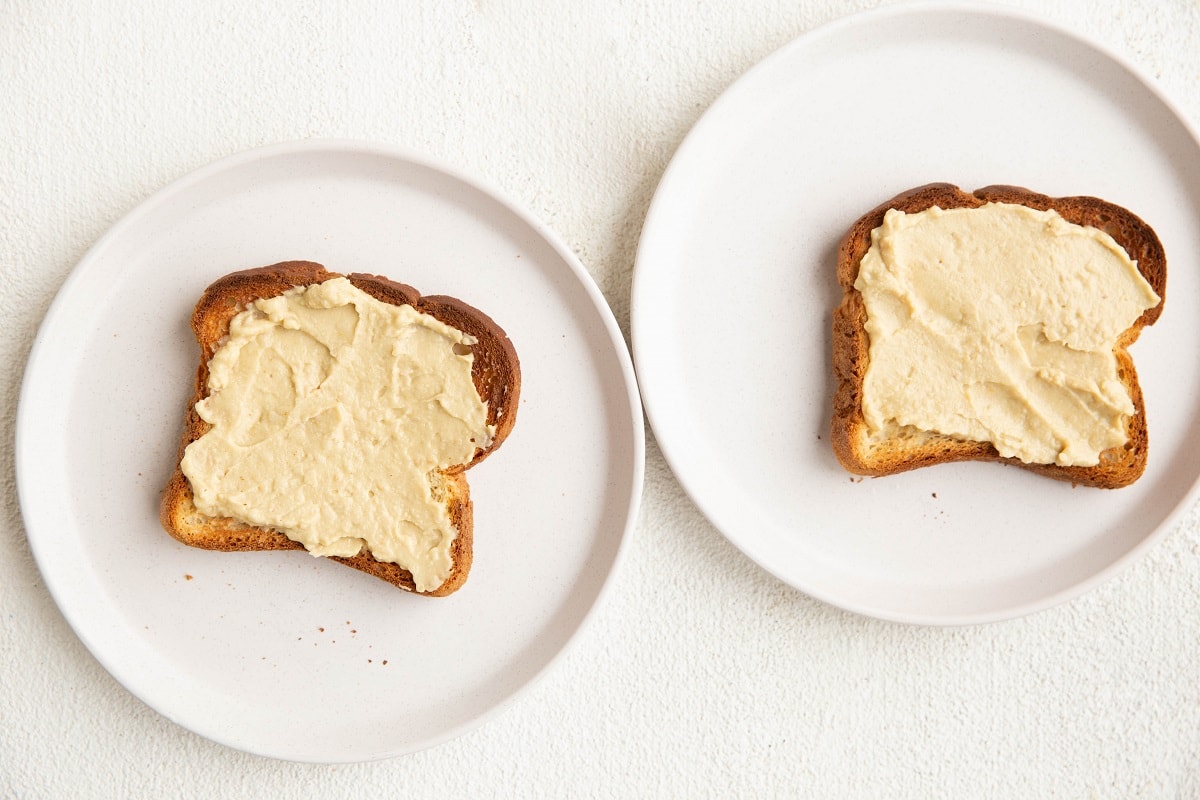 Two slices of toast with hummus smeared on top.