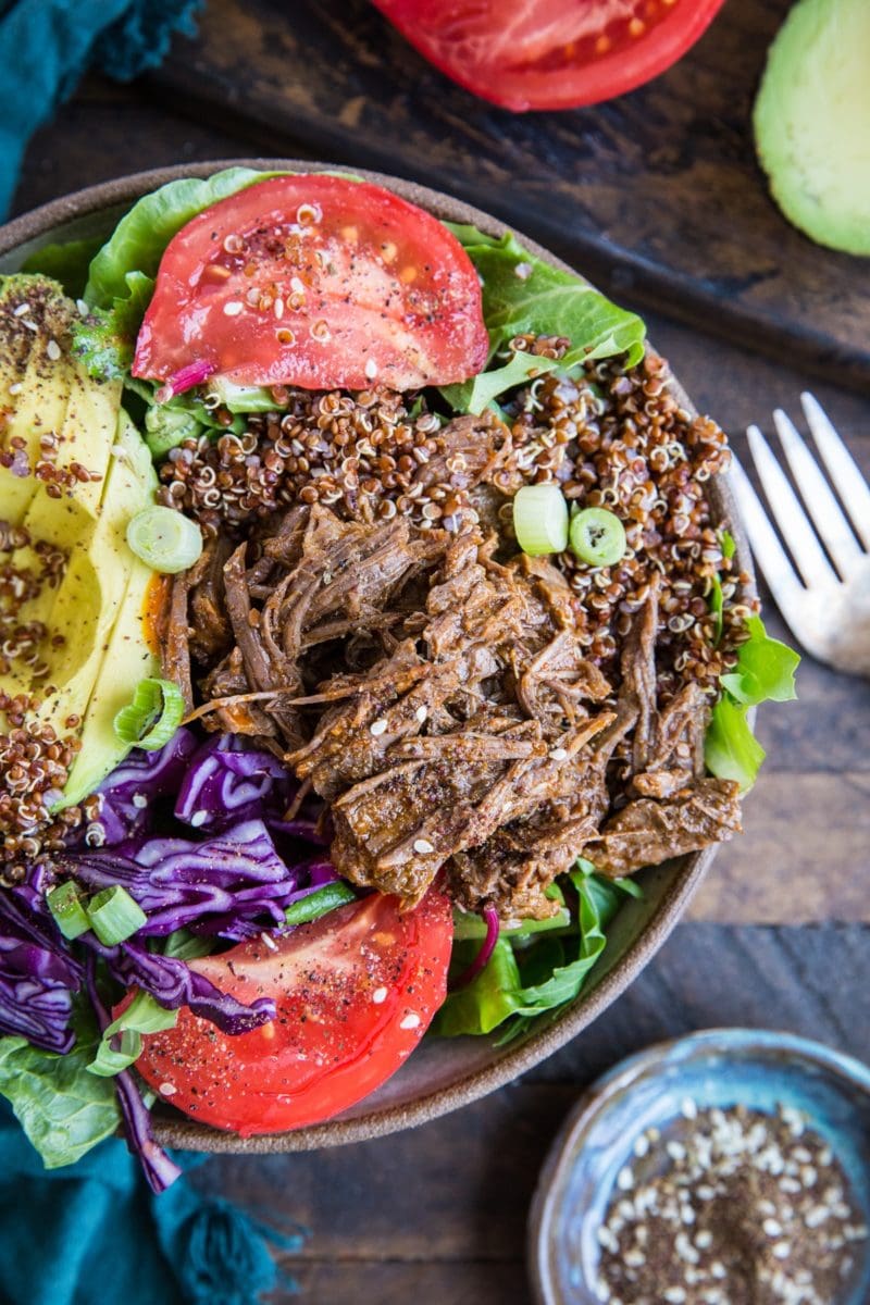 Big bowl full of barbacoa beef, greens, cabbage, tomatoes, quinoa, and avocado. Ready to eat.