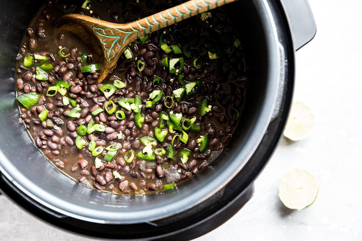 Pressure cooker full of cooked black beans, ready to serve.