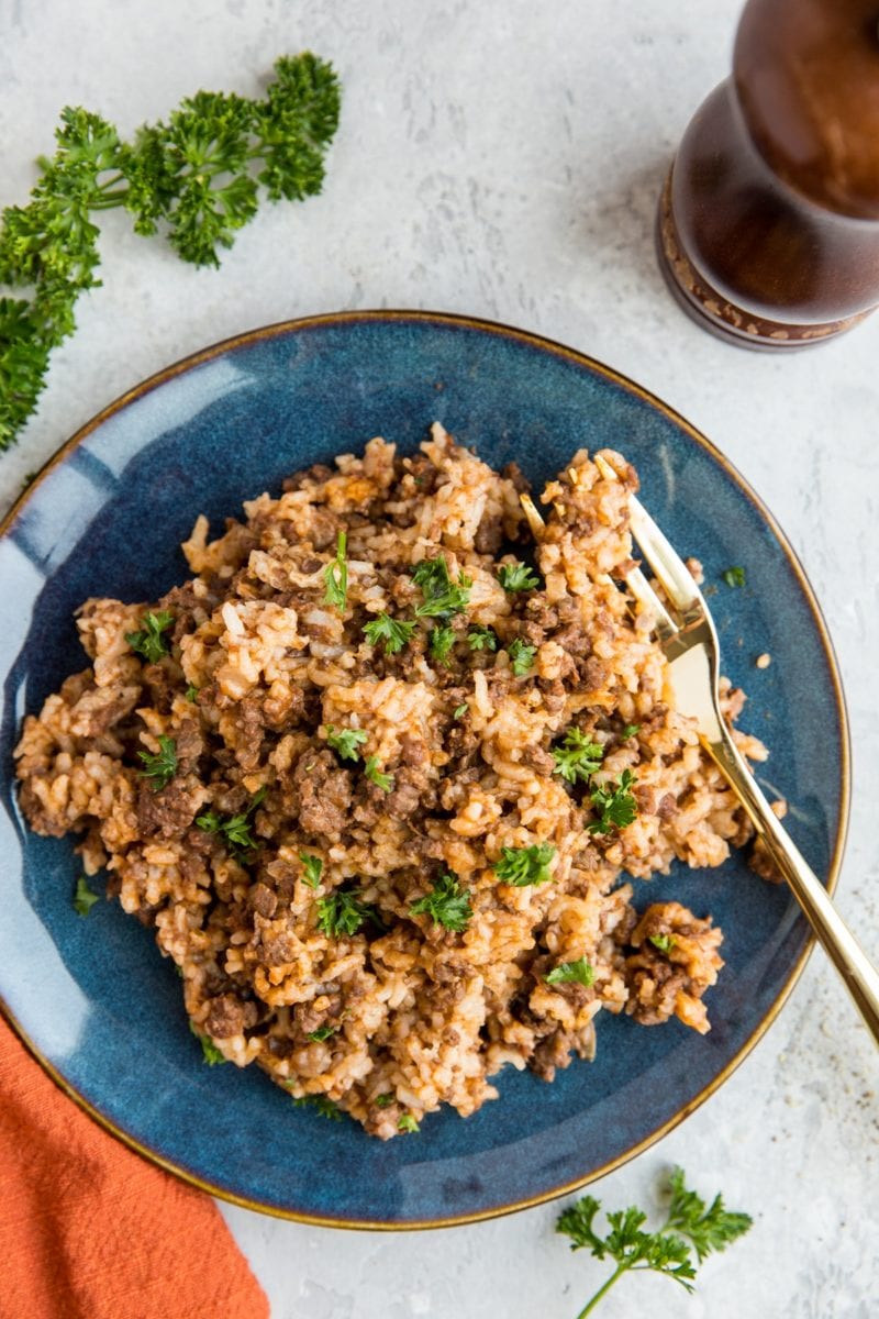 Blue plate of hamburger helper with rice, sprinkled with parsley.