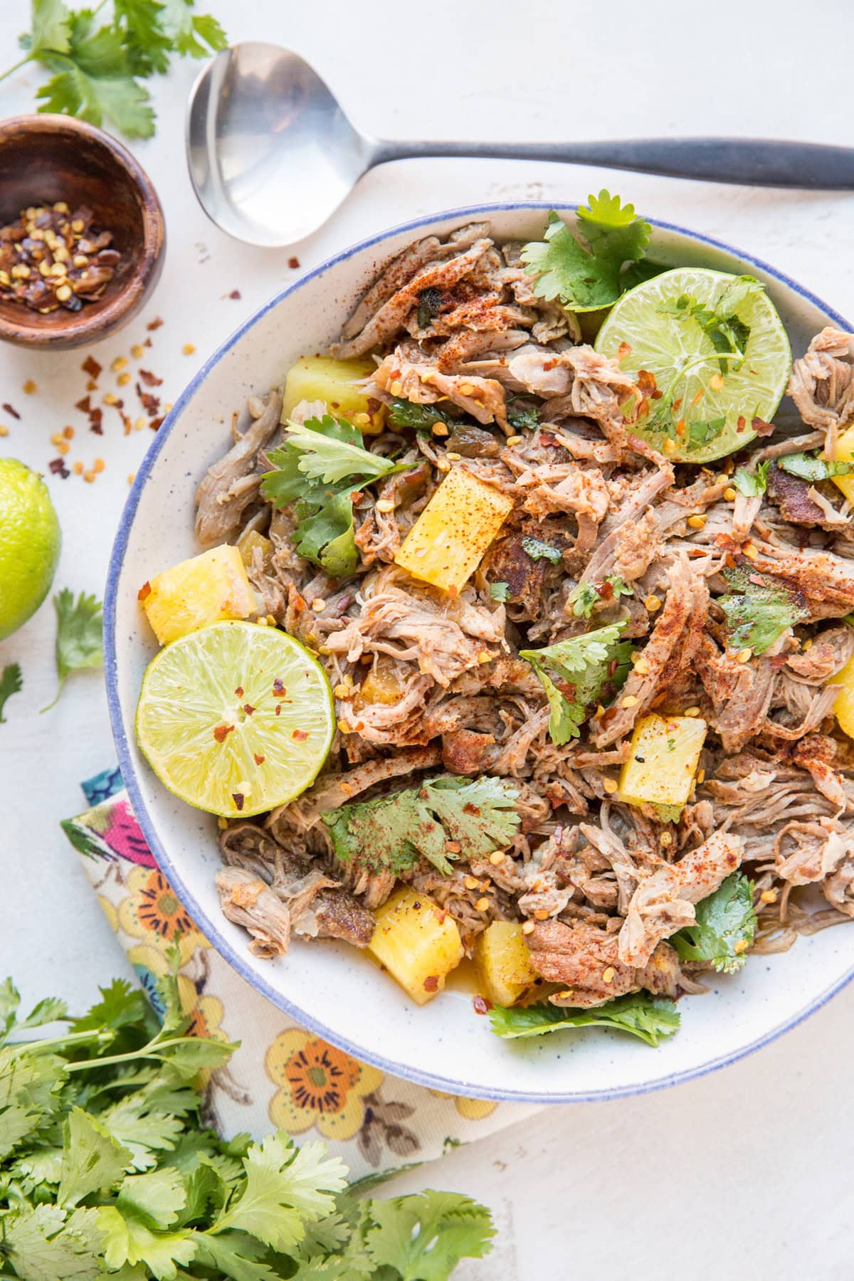 pulled pork with pineapple and cilantro in a bowl with a serving spoon, ready to serve.