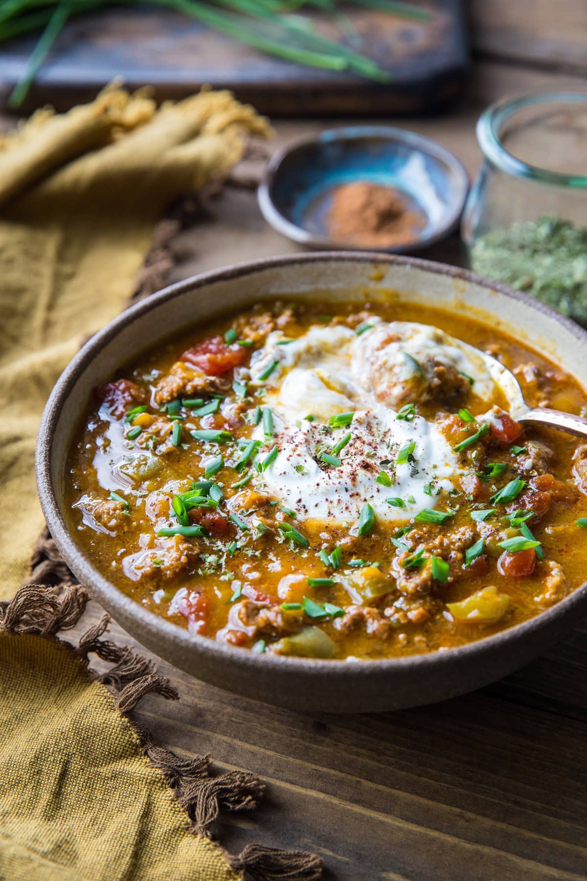 large bowl full of chili with a dollop of sour cream or yogurt on top, sprinkled with chives and ready to serve.