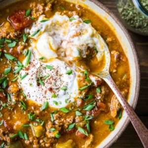 Large pottery bowl full of pumpkin chili with a spoon. Ready to serve.