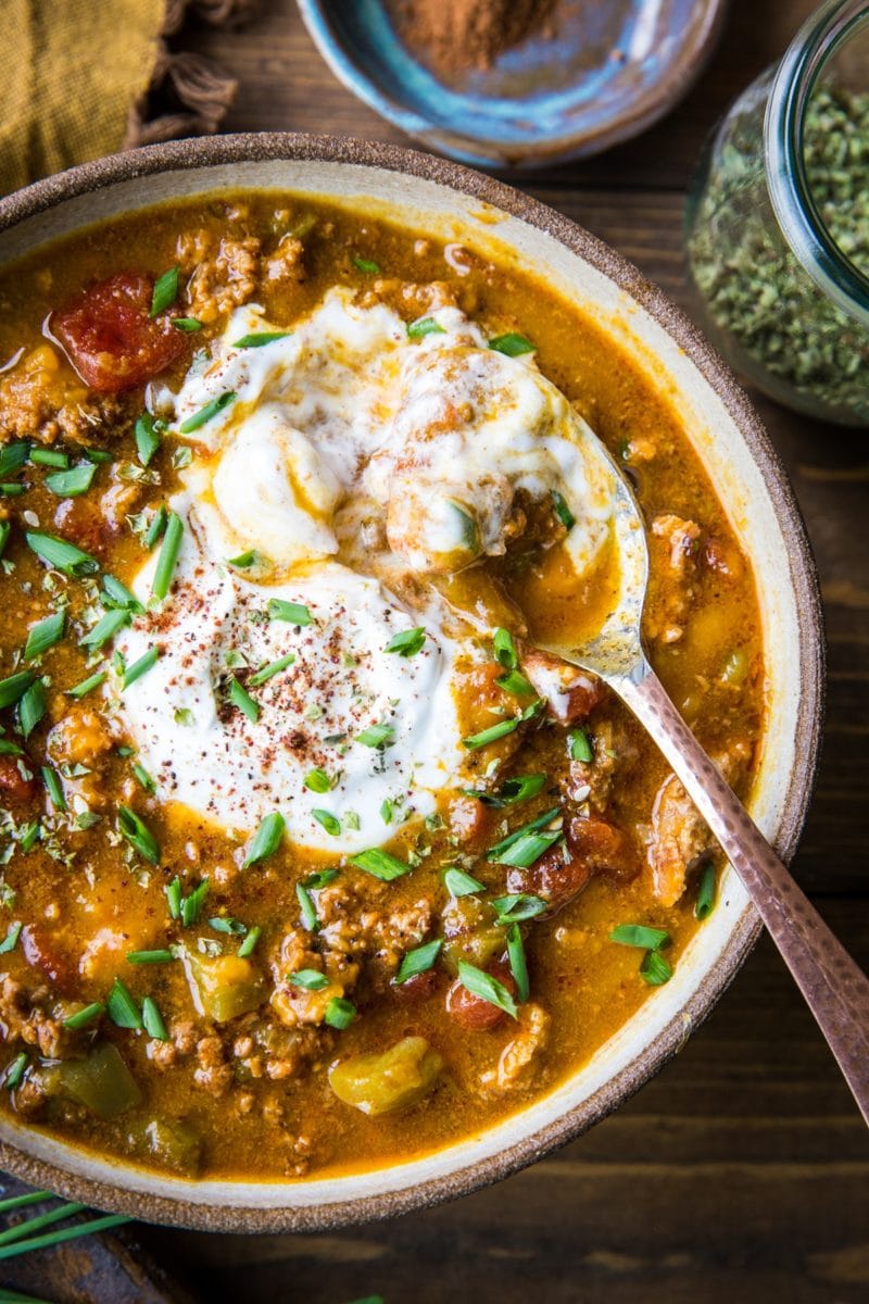 Large pottery bowl full of pumpkin chili with a spoon. Ready to serve.