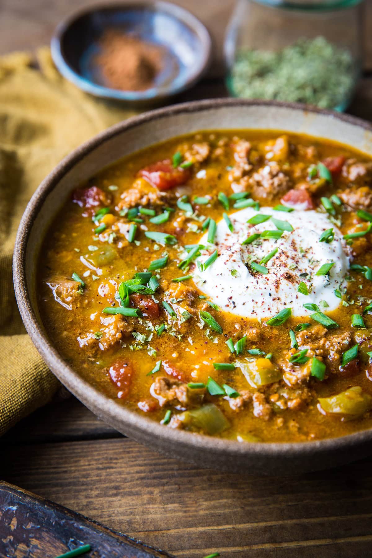 Ceramic bowl of paleo pumpkin chili with yogurt and chives on top.