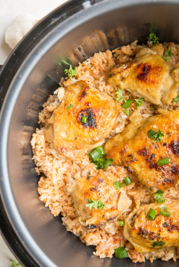 Instant Pot full of Spanish rice and chicken thighs. Garnished with chopped green onions and ready to serve.