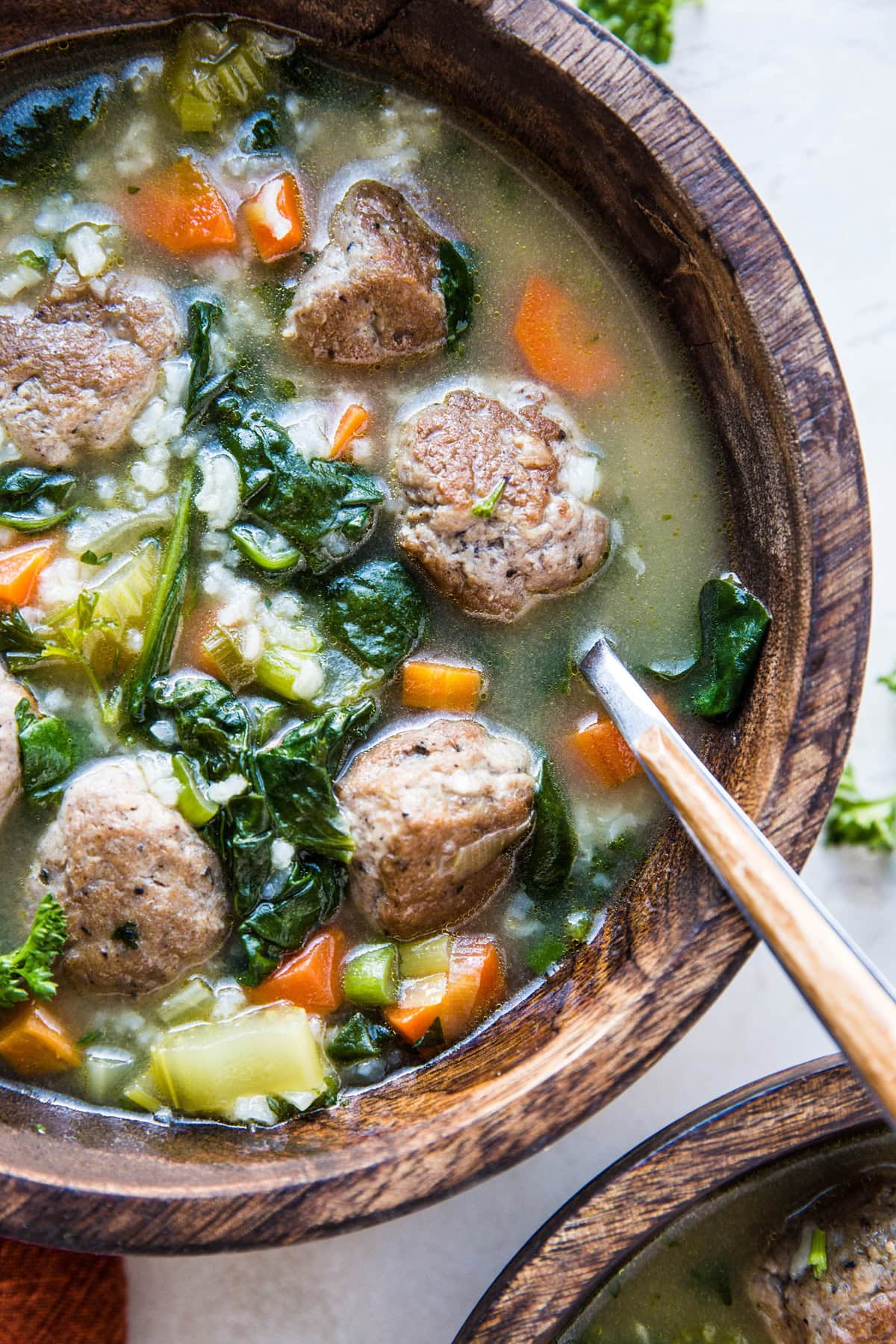 Two wooden bowls of Italian Wedding Soup, ready to serve.