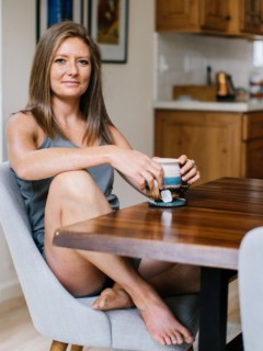 Julia Mueller sitting at a table holding a mug of tea