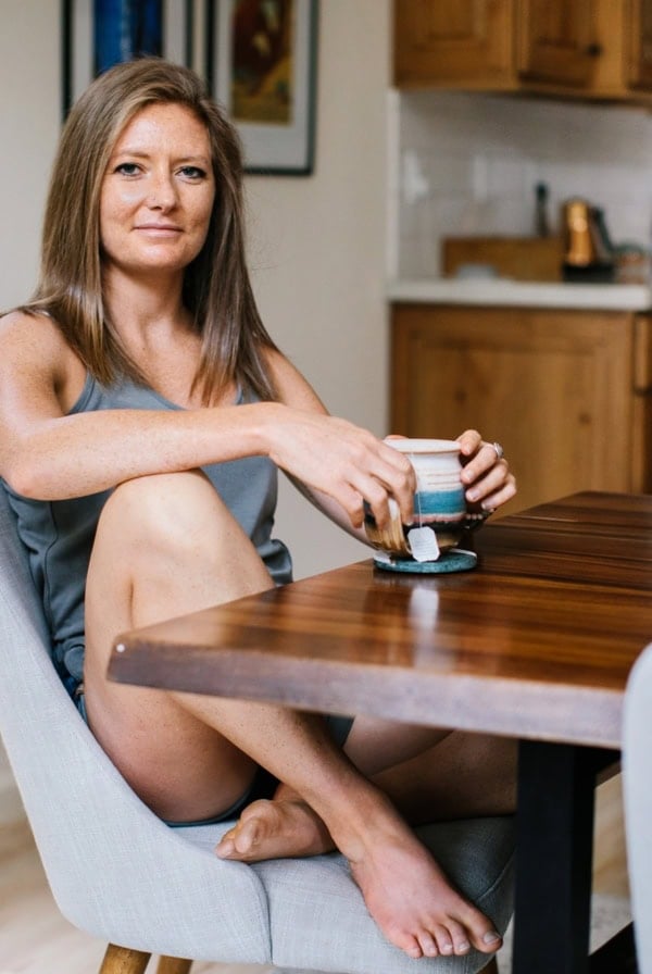 Julia Mueller sitting at a table holding a mug of tea