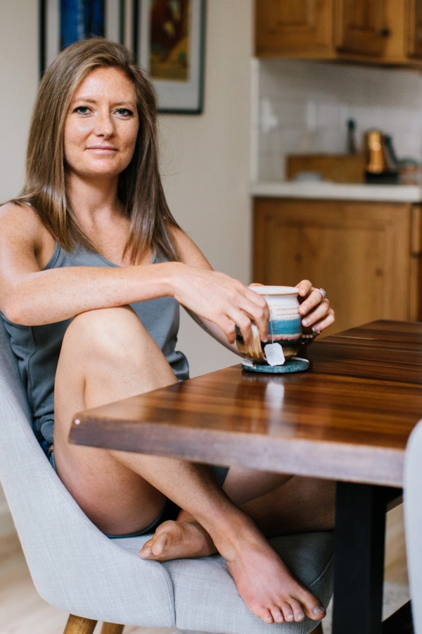 Julia Mueller sitting at a table holding a mug of tea