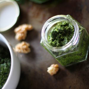 Kale Pesto in a jar with walnuts to the side.
