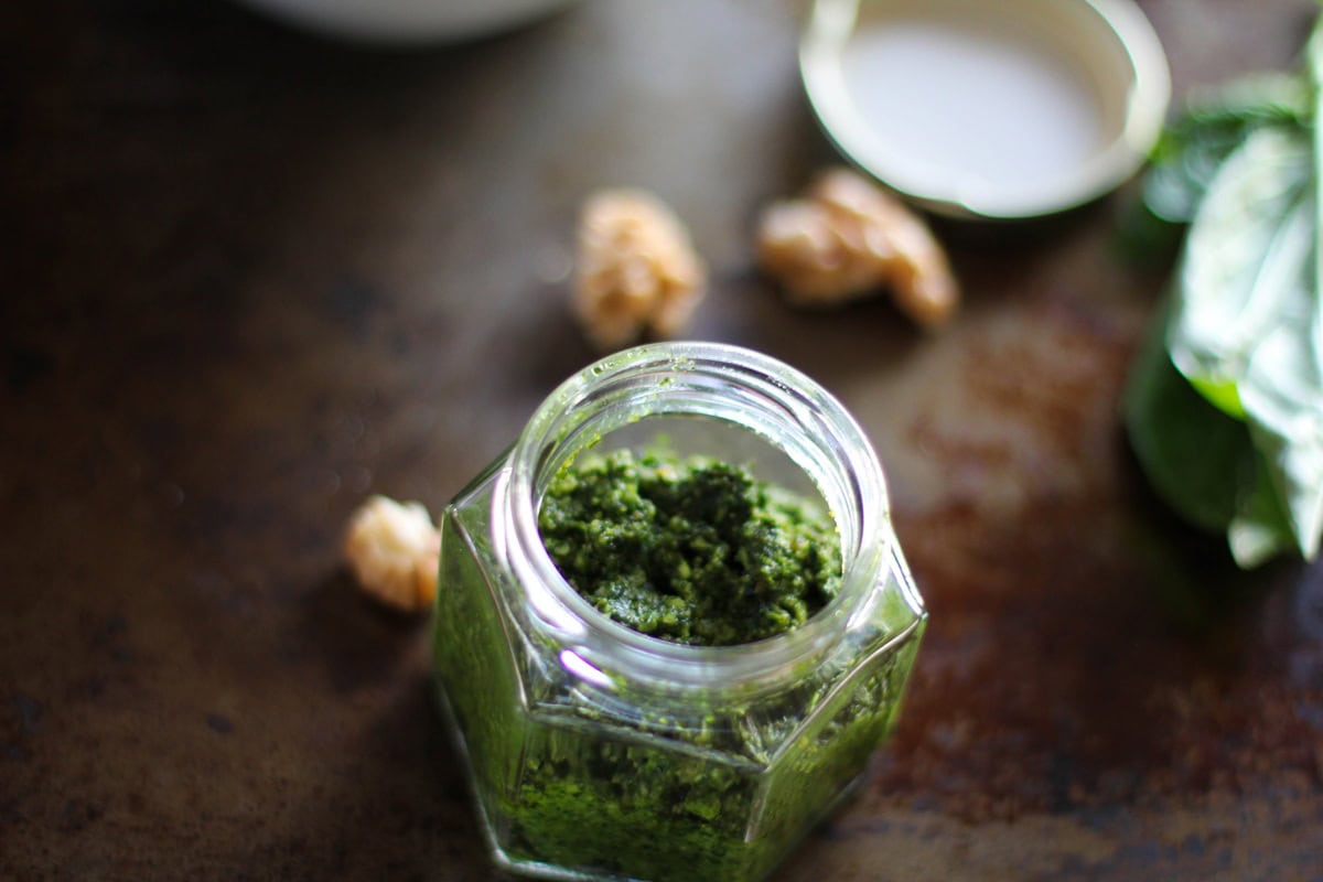 Kale Pesto in a jar with walnuts in the background