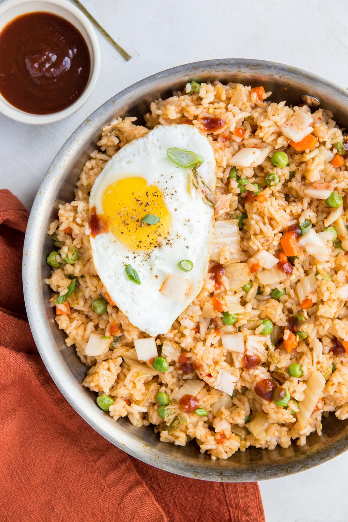 Stainless steel pot of fried rice with a fried egg on top, ready to serve.