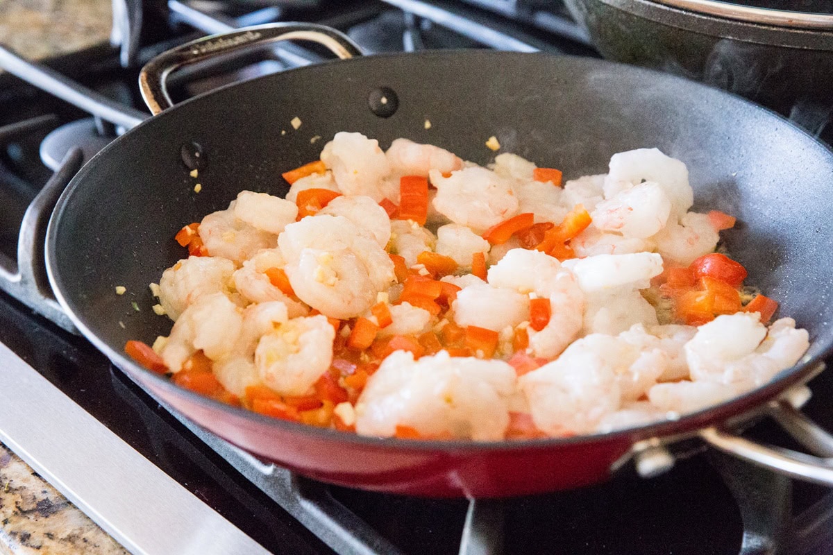 shrimp and vegetables sauteing in a skillet to make kung pao shrimp.
