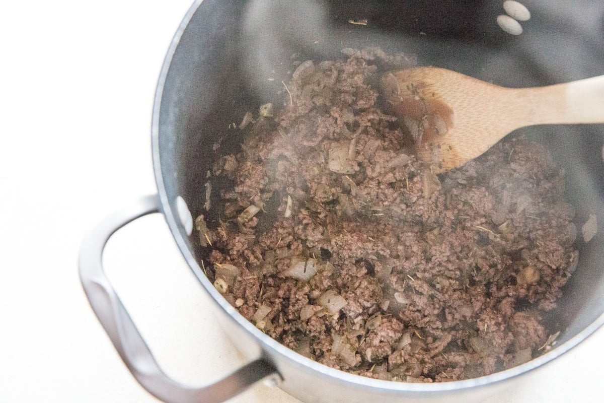Large pot full of sauteed onion and browned ground beef.