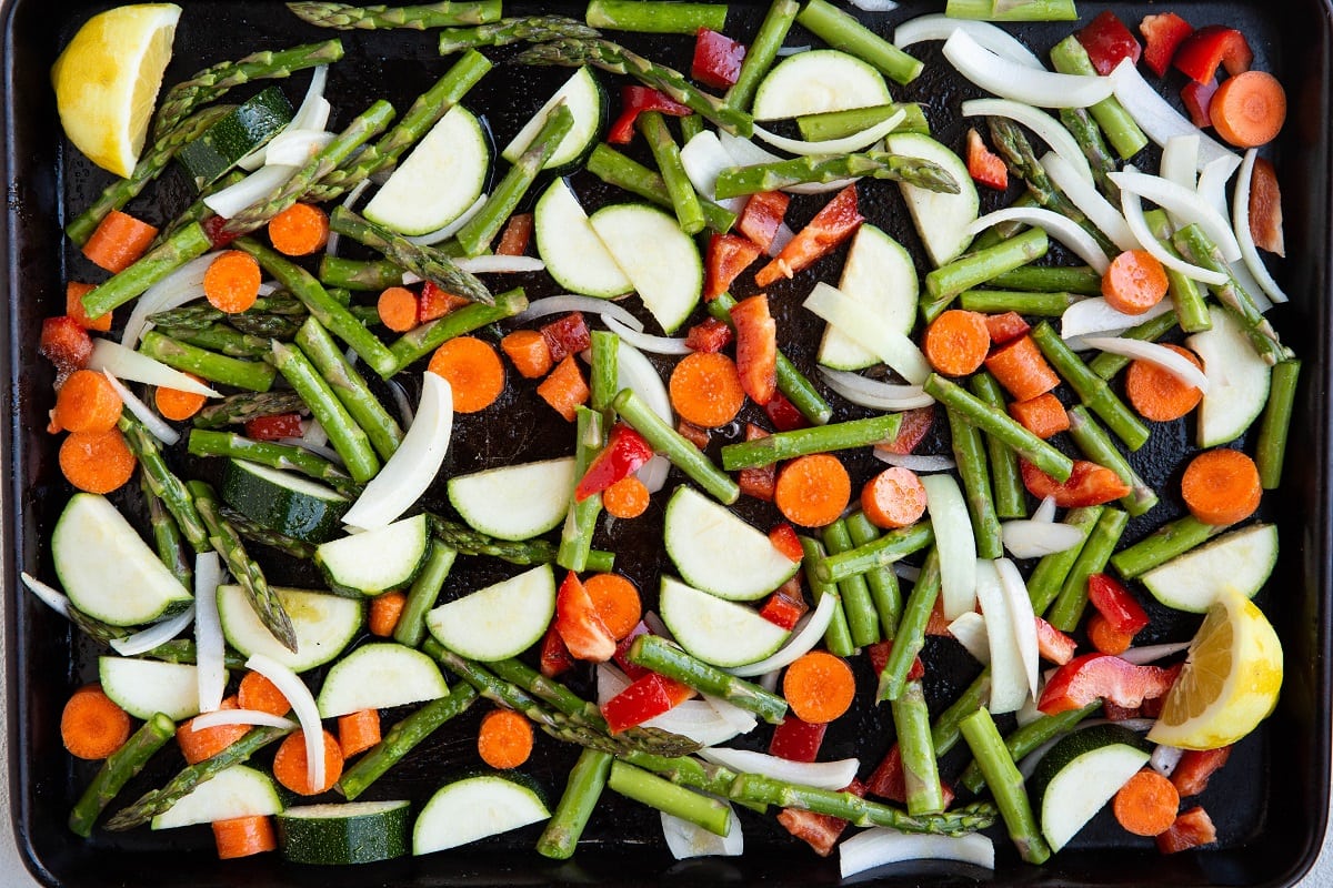 Raw vegetables spread out on a sheet pan, ready to roast.