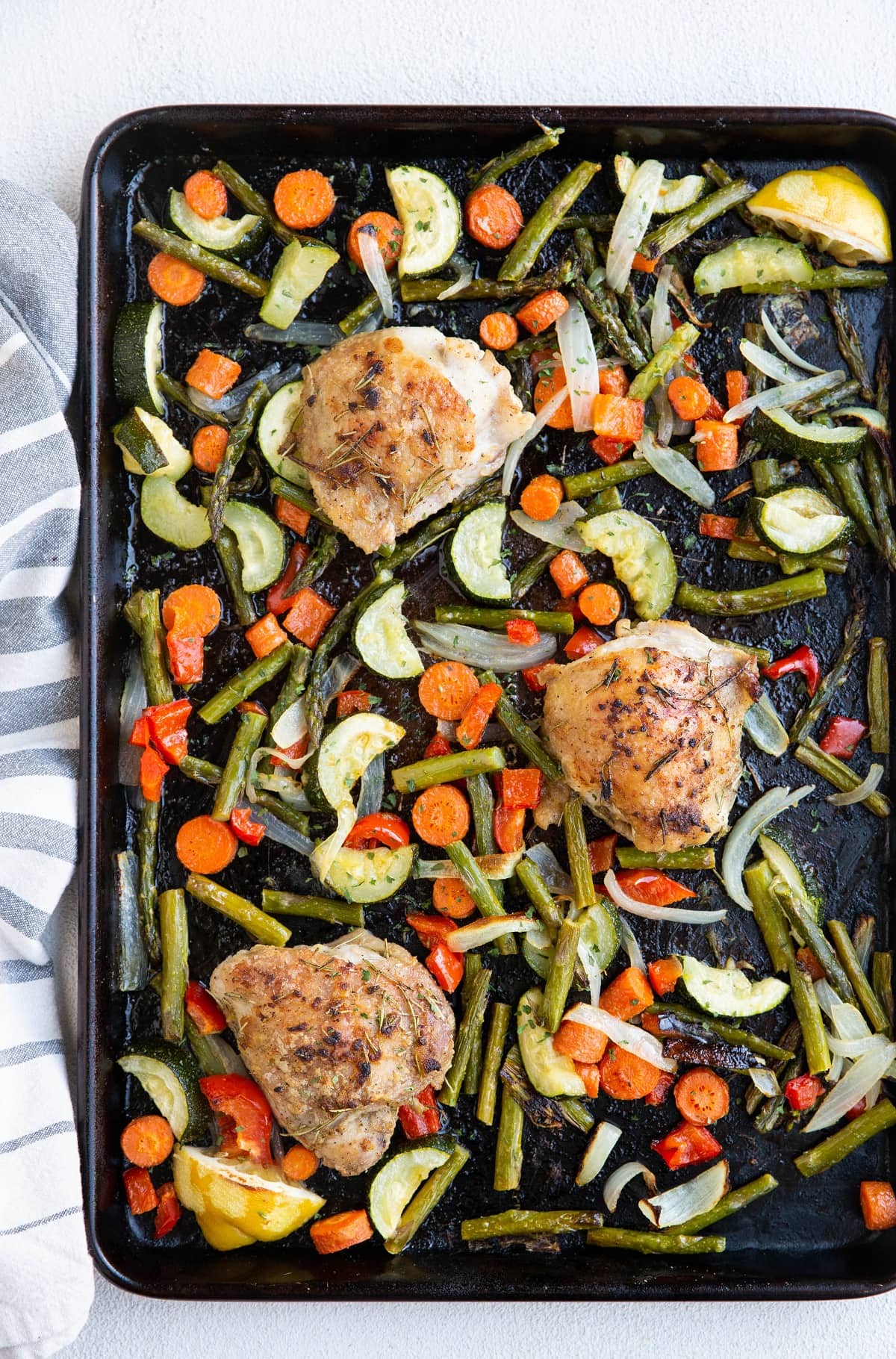 Large sheet pan of veggies and chicken thighs fresh out of the oven.