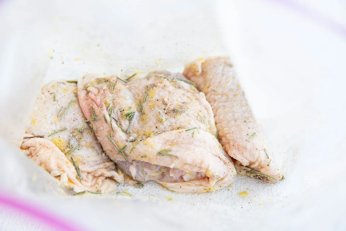 Raw chicken thighs in a zip lock bag with lemon rosemary marinade.