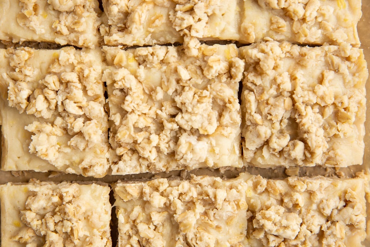 Squares of lemon crumb bars sliced on a sheet of parchment paper.