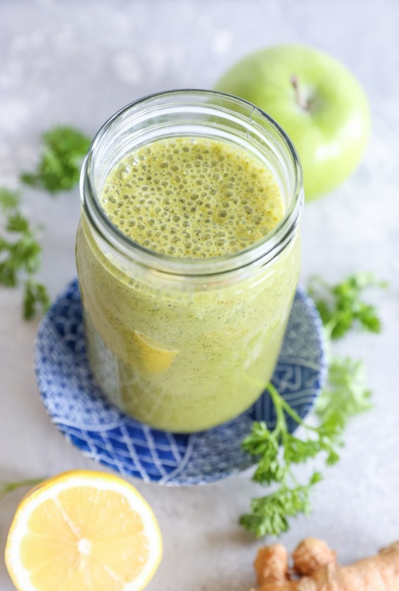 glass of liver detox smoothie with fresh lemon and parsley to the side.