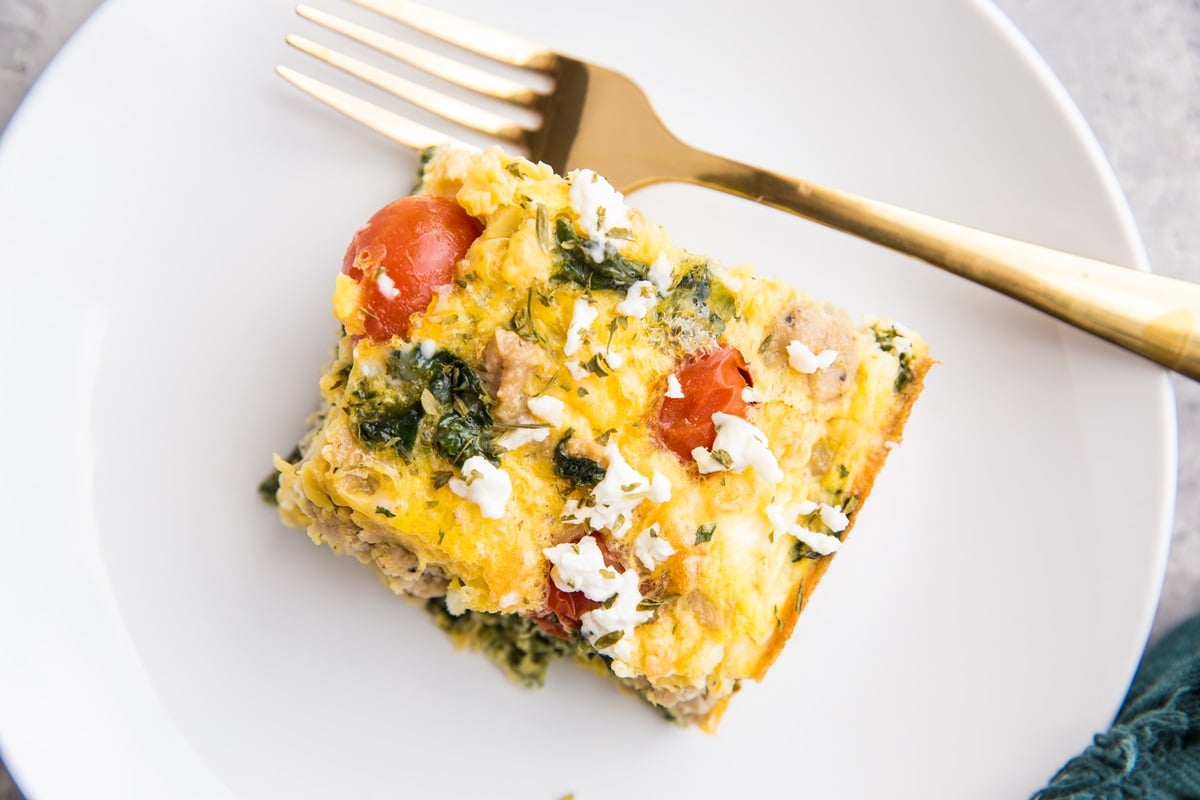 Slice of low-carb breakfast casserole on a white plate with a fork.