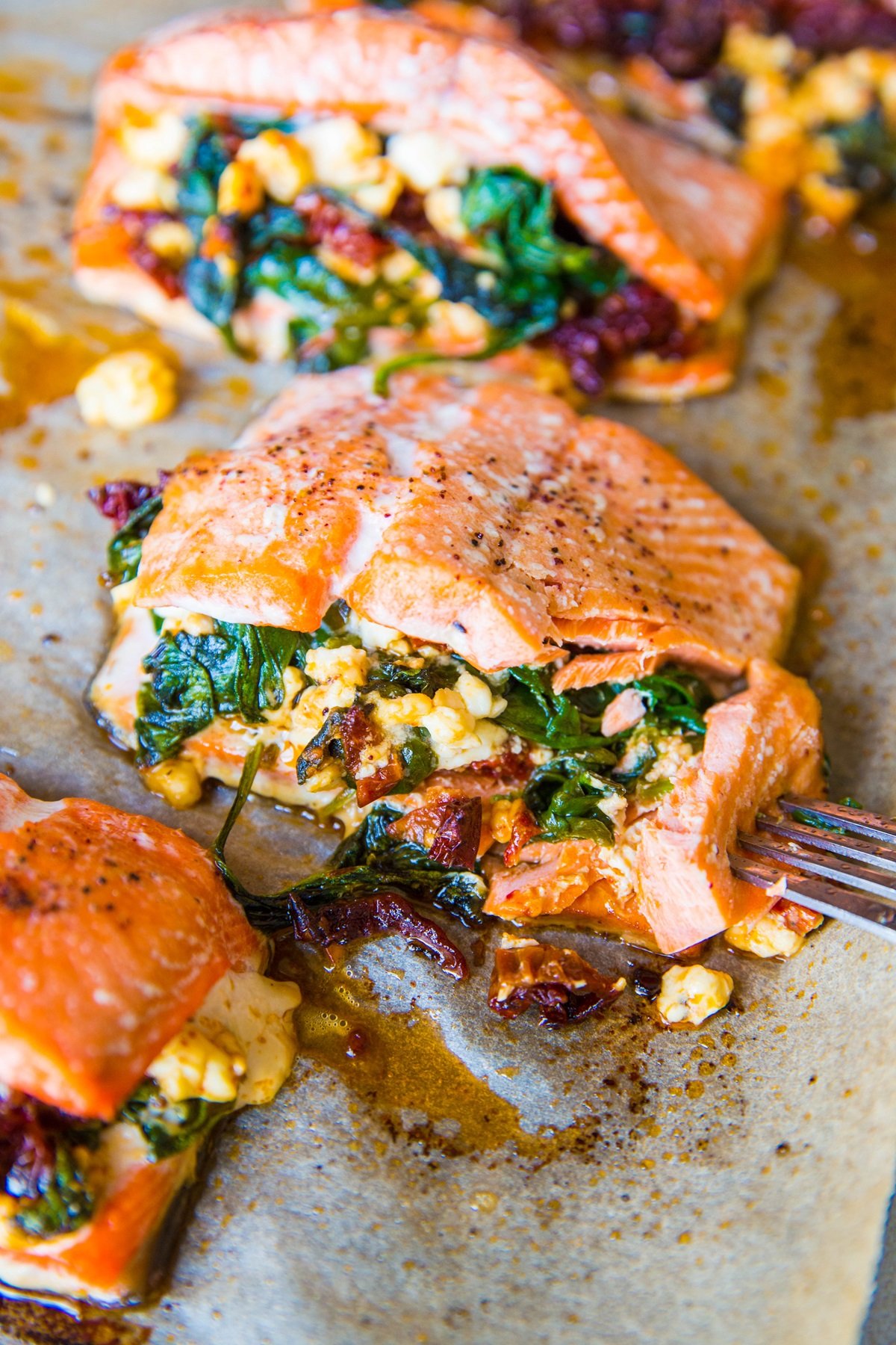 Mediterranean Stuffed Salmon on a parchment lined baking dish, fresh out of the oven and ready to eat.