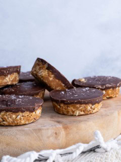 Wooden cutting board with chocolate oatmeal peanut butter cups with sea salt sprinkled on top.