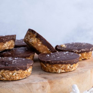 Wooden cutting board with chocolate oatmeal peanut butter cups with sea salt sprinkled on top.