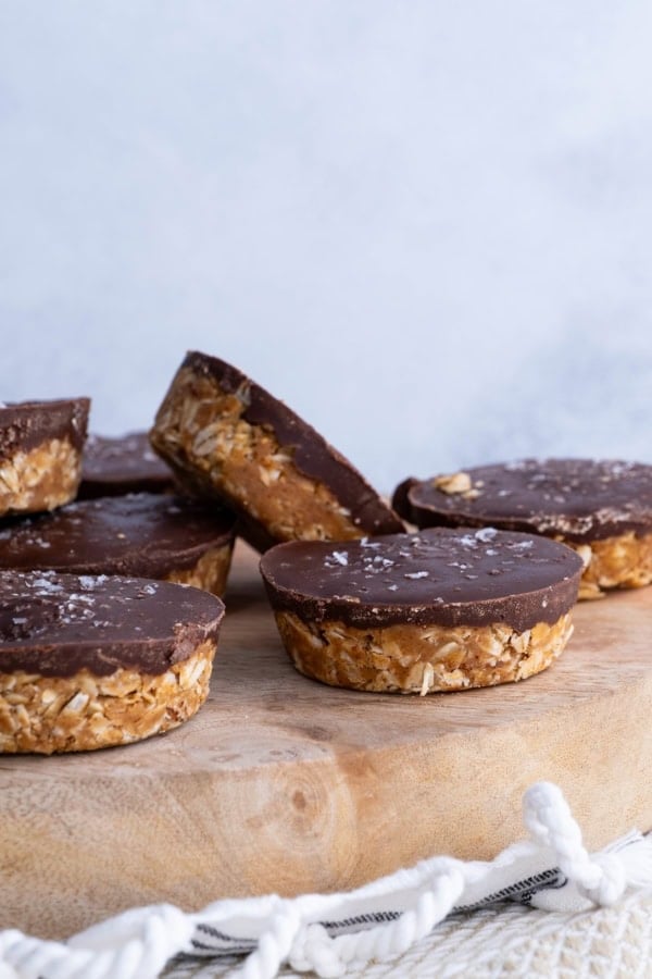 Wooden cutting board with chocolate oatmeal peanut butter cups with sea salt sprinkled on top.