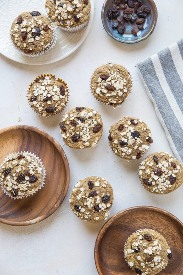 Oatmeal Raisin Muffins on wooden plates and more scattered around on a backdrop.