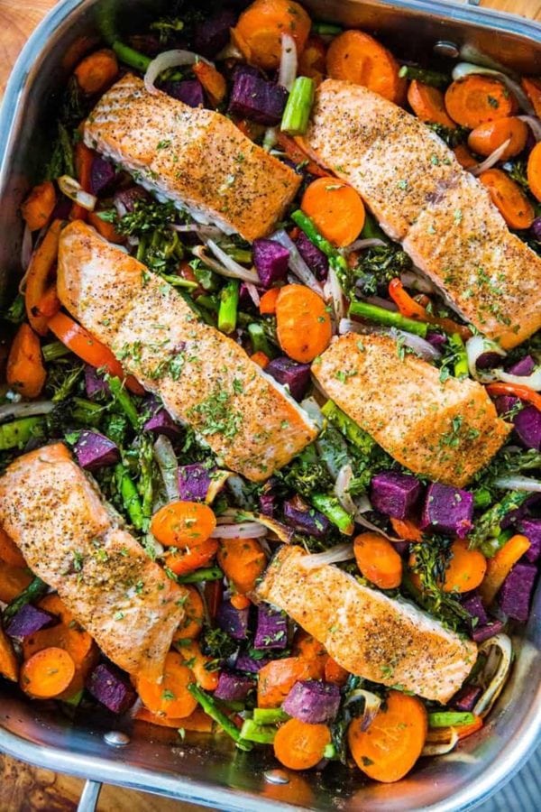 Large pan full of roasted vegetables and salmon, ready to eat.