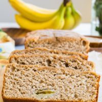 Loaf of paleo banana bread cut into slices on a cutting board.