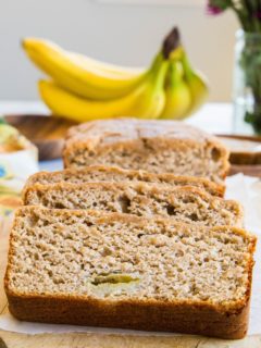Loaf of paleo banana bread cut into slices on a cutting board.