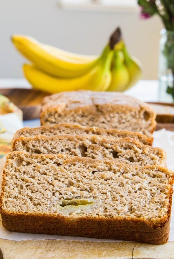 Loaf of paleo banana bread cut into slices on a cutting board.