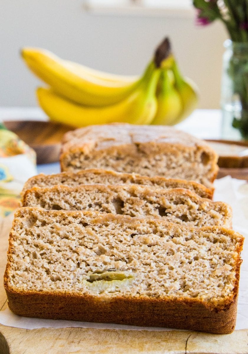 Loaf of paleo banana bread cut into slices on a cutting board.