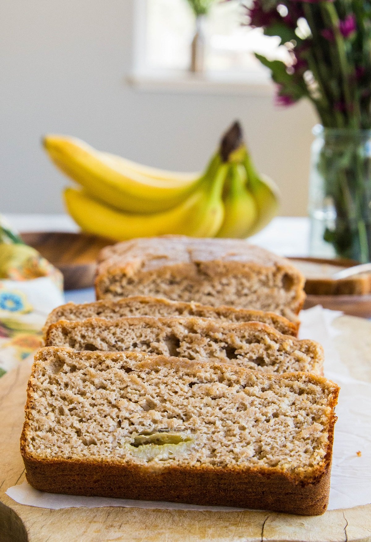 Loaf of paleo banana bread cut into slices on a wooden cutting board