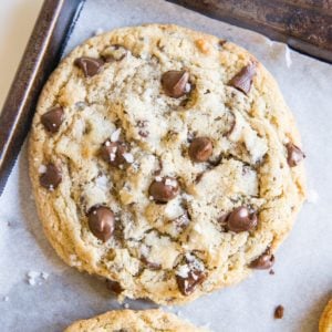 Large baking sheet with giant paleo chocolate chip cookies on top, sprinkled with sea salt.