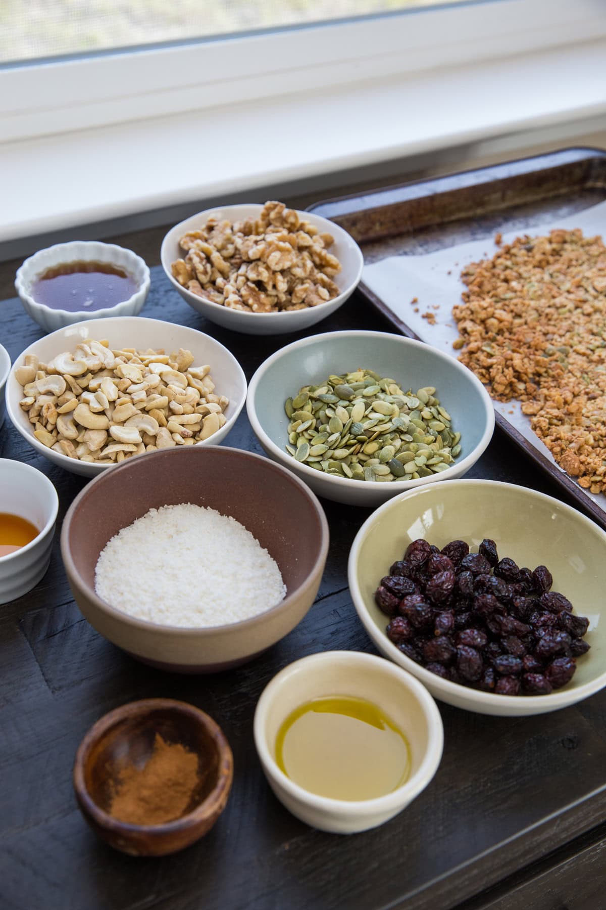 Bowls of ingredients for paleo granola on a tabletop, ready to be used.